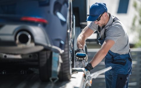 Towing Company Worker Securing Vehicle on the Truck Platform